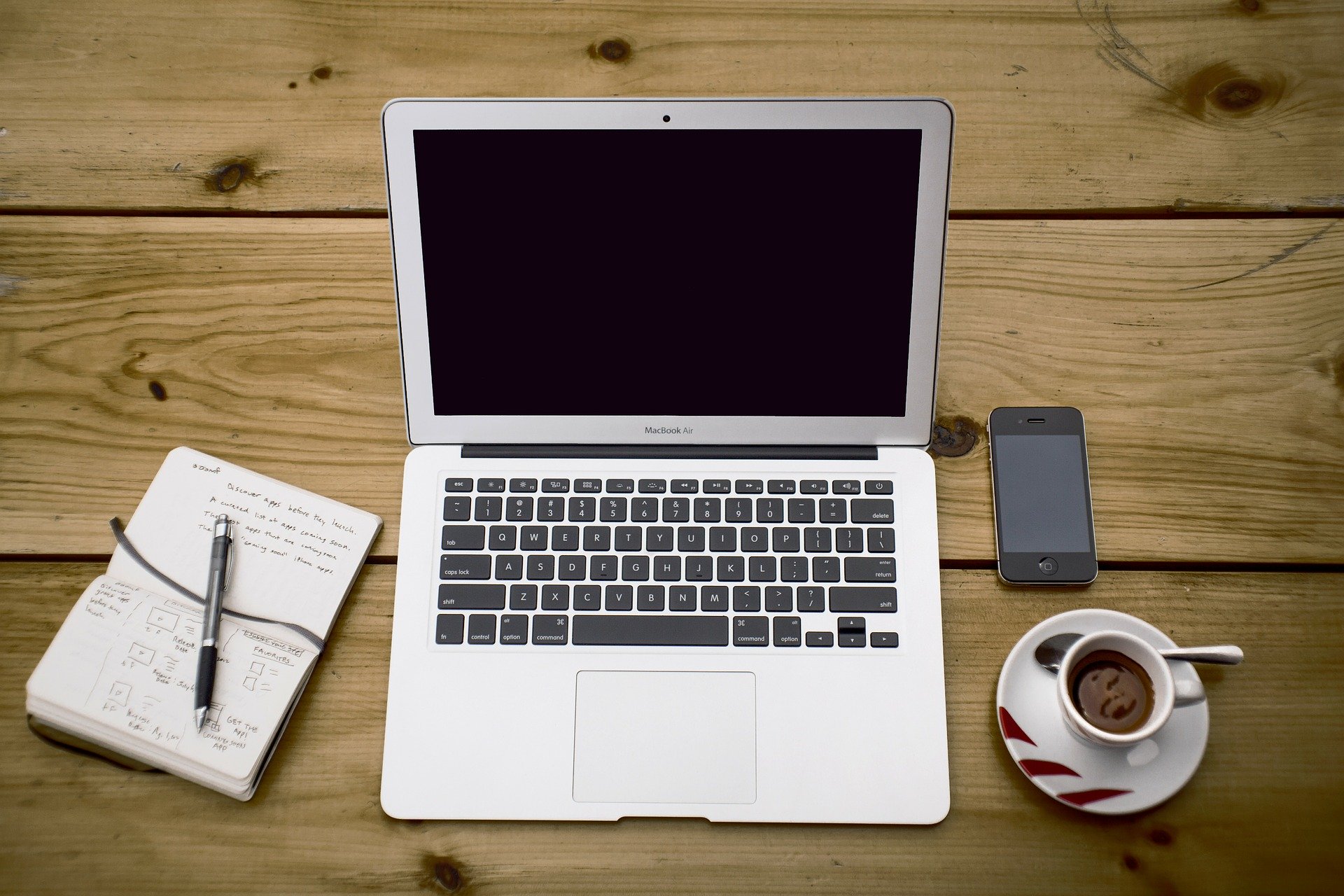 Image of a laptop, notebook, phone, coffee set up to work