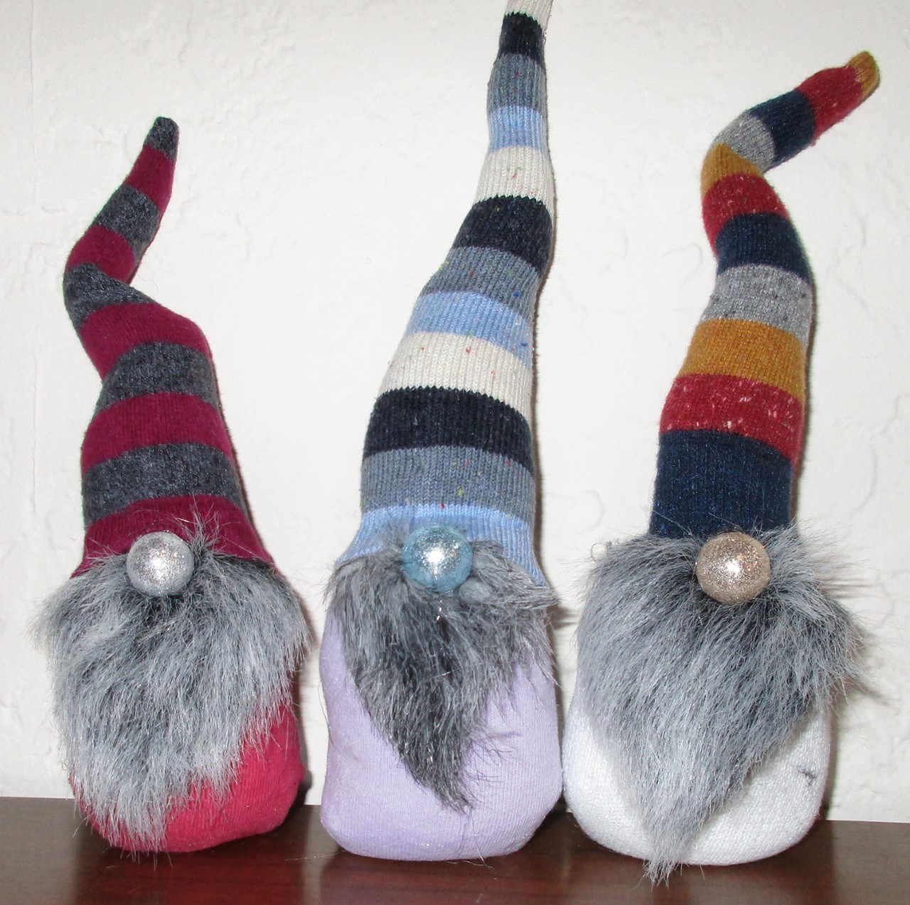 three cloth gnomes with striped hats and gray fur beads