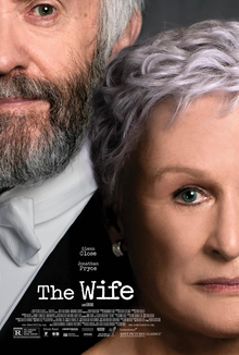 Extremely closeup portrait of an older woman staring directly into the camera (Glenn Close) with her husband, slightly off to the side, behind her