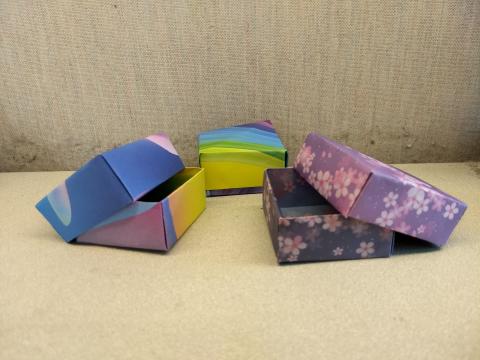 three tiny, colorful origami boxes with lids