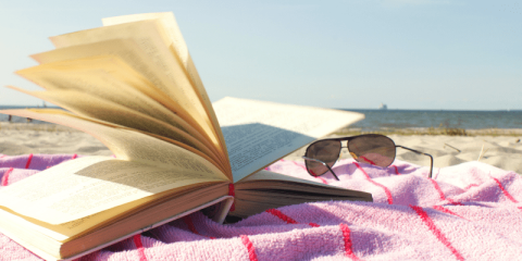 open book on towel with sunglasses on the beach