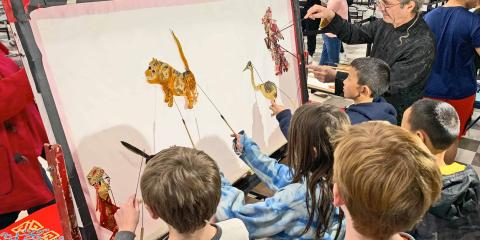 Children creating shadow puppets of various animals: dog, lion, bird