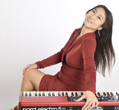 miho sitting at her piano in a red dress
