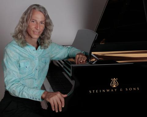 Paul Joseph posing at a steinway grand piano