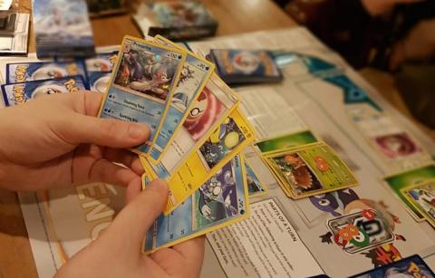 Hands holding Pokemon cards.