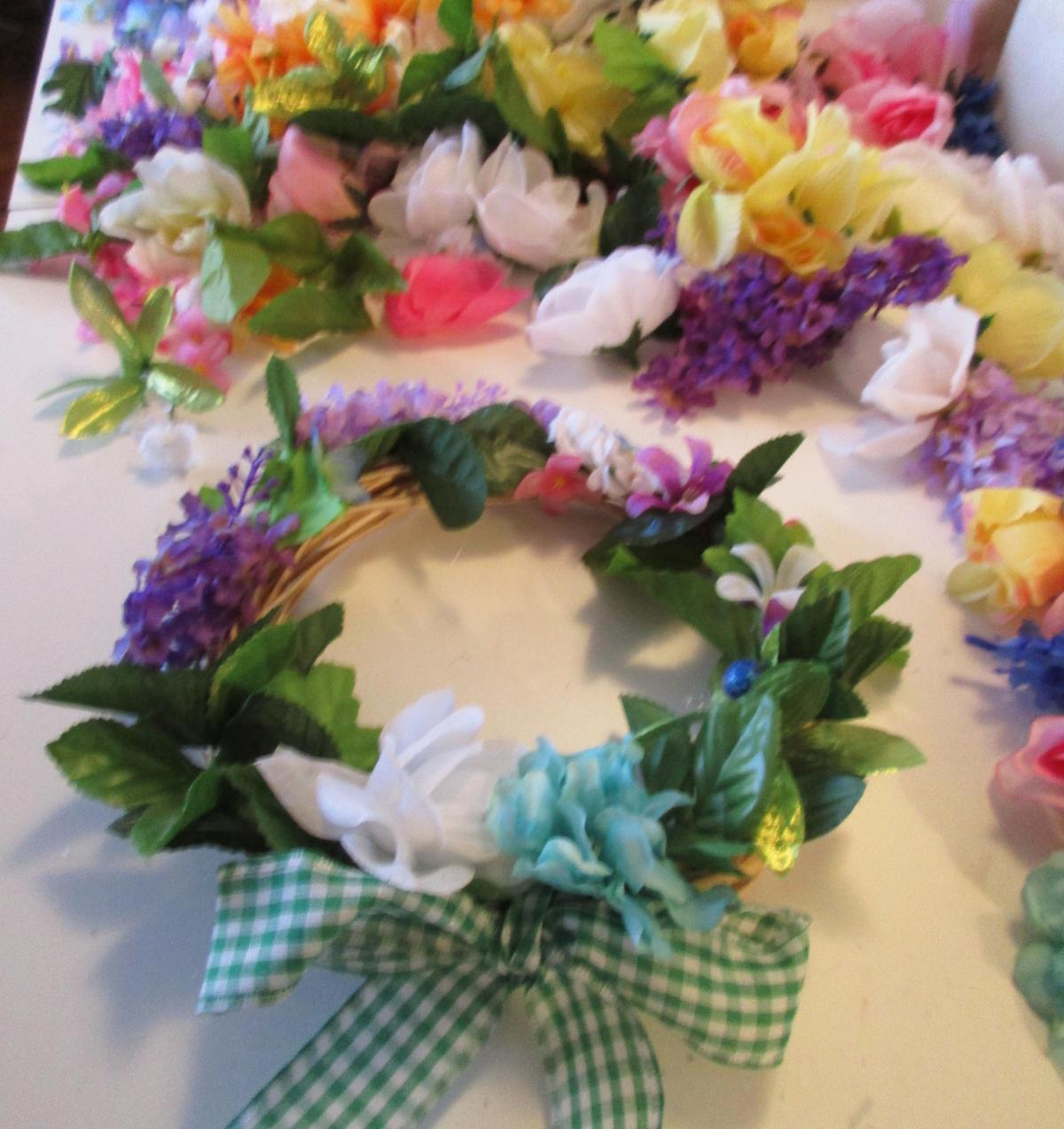 wreath covered in flowers and wreaths, with a green checked ribbon at the bottom