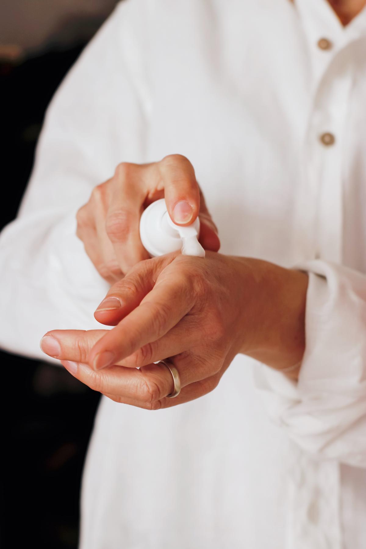 woman putting lotion on hands