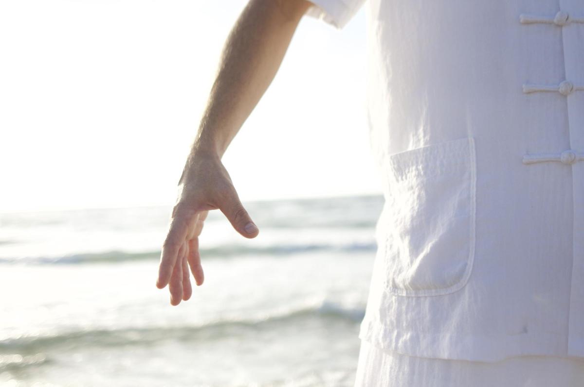 close up shot of hands opening in front of an ocean