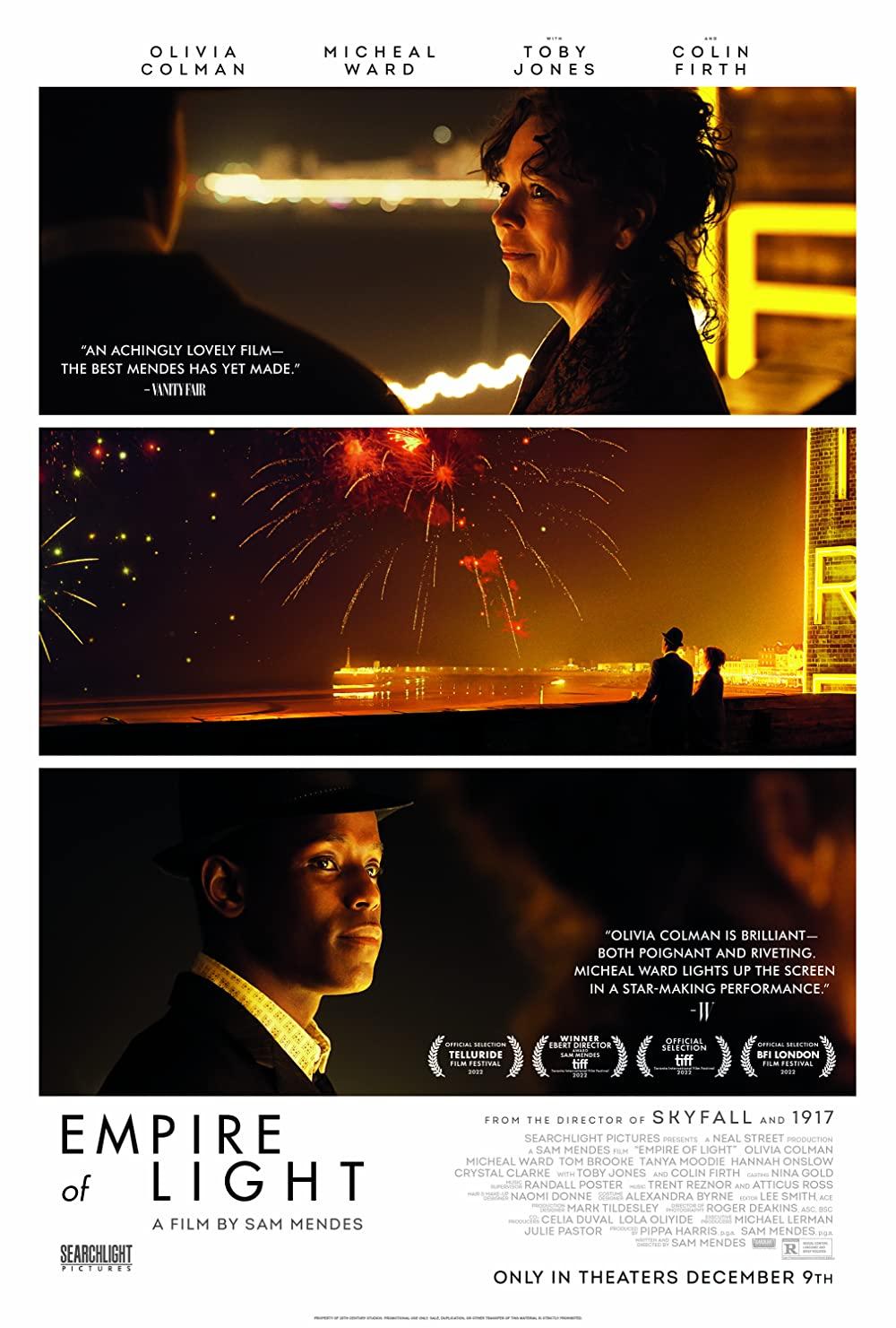 A man and a woman look out towards fireworks while aglow from the light of the cinema